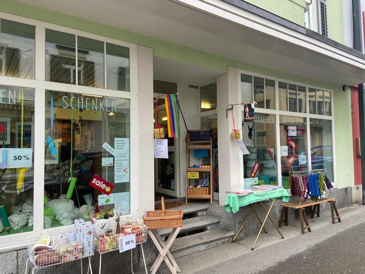 Noch bis Ende Mai gilt: 50 Prozent Ermässigung auf alle Produkte. Ein Bastelladen von aussen. Vor dem Eingang stehen Körbe und kleinere Waren.